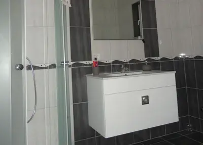 a bathroom with a sink and a shower with a mirror at Apartments A&D in Bihać