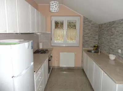 a kitchen with white cabinets and a white refrigerator at Apartments A&D in Bihać