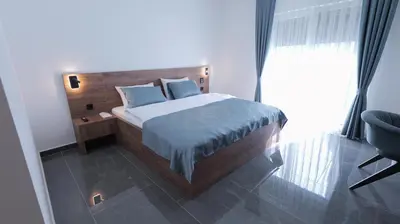 a bedroom with a bed with blue pillows and a chair at Belvedere rooms A&E in Velika Kladuša