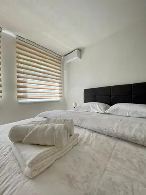 a white bedroom with a large bed with a window at Apartment Diletta in Banja Luka