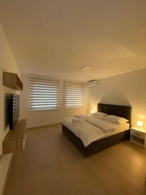 a bedroom with a large bed and two windows at Apartment Diletta in Banja Luka