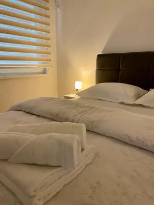 a bedroom with a bed with white sheets and a window at Apartment Diletta in Banja Luka