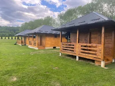 a row of wooden lodges in a field of grass at Etno zona Oaza mira in Donji Vakuf