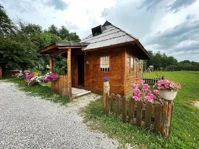 a small wooden house with flowers in a yard at Etno zona Oaza mira in Donji Vakuf