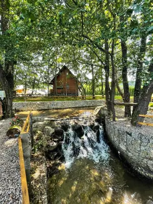 a small waterfall next to a log cabin at Etno zona Oaza mira in Donji Vakuf