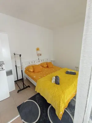 a bedroom with two beds with yellow sheets and a tripod at Studio apartman Nejra in Bihać