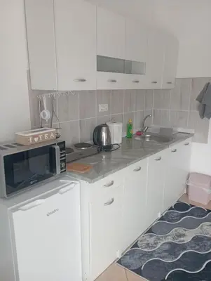 a kitchen with white cabinets and a microwave at Studio apartman Nejra in Bihać