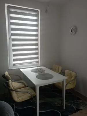 a white table and chairs in a room with a window at Studio apartman Nejra in Bihać