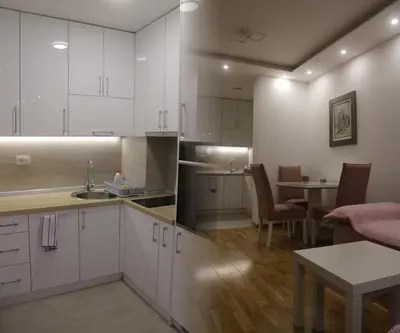 a kitchen with white cabinets and a table and a dining room at Nela Bl in Banja Luka