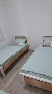 two beds in a room with white walls and wooden floors at Vila Didan-apartmani in Bihać