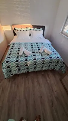 a bedroom with a large bed with a wooden floor at Vila Didan-apartmani in Bihać