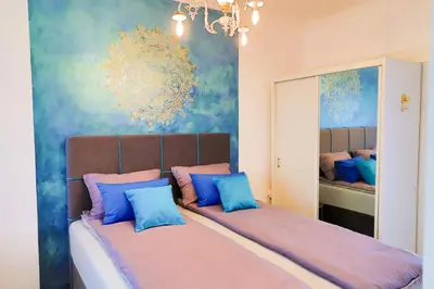 a bedroom with two beds with blue and pink pillows at Apartman SUMI in Bihać