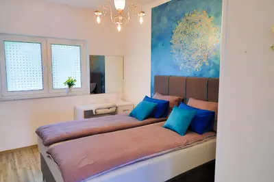 a bedroom with a large bed with blue pillows at Apartman SUMI in Bihać