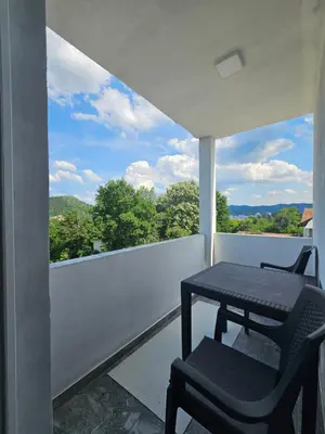 a table and a chair on a balcony with a view at Apartmani gradina Tuzla in Tuzla