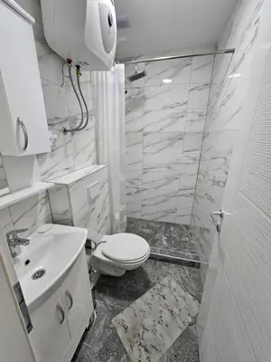 a white bathroom with a toilet and a sink at Apartmani gradina Tuzla in Tuzla