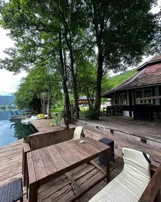 a wooden table and chairs on a deck next to the water at Holiday house 