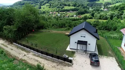 a small white house with a car parked next to it at Kuća za odmor GAVRIĆ in Mrkonjić Grad