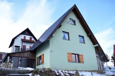 a white house with a gambrel roof at Brano in Kupres