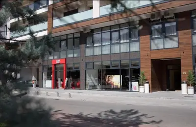 a large glass building with a red door on a street at Central Luxe in Banja Luka