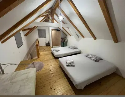 two beds in a attic room with wooden floors at Holiday Home AZER in Visoko