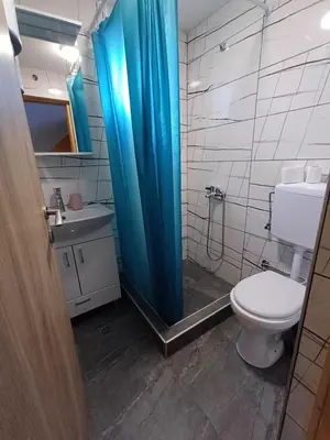 a bathroom with a toilet and a blue shower curtain at Holiday Home AZER in Visoko
