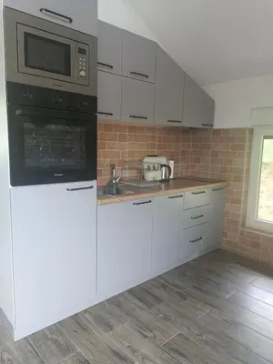 a kitchen with white cabinets and a microwave at Zen Loft in Tuzla