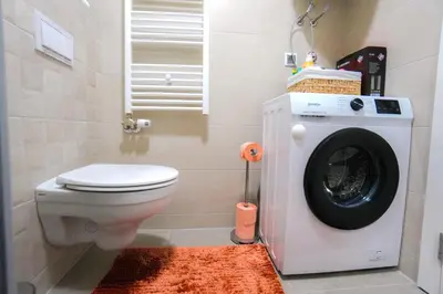 a bathroom with a toilet and a washing machine at Elegance Apartmani Doboj Stan na dan in Doboj