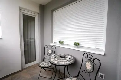 a table and chairs in a room with a window at Elegance Apartmani Doboj Stan na dan in Doboj