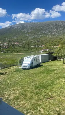 a white truck parked in a field with a trailer at Camp Tommy in Jaklići