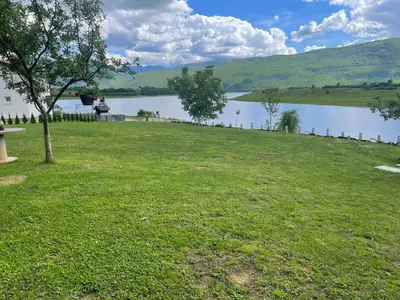 a person sitting on a bench next to a lake at Camp Tommy in Jaklići