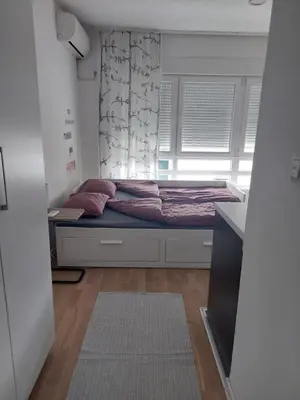 a small bed in a room with a window at Urban Studio Apartment in Tuzla