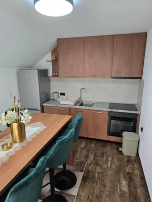 a kitchen with a wooden table with chairs and a sink at Apartmani Zlatna Kruna in Banja Luka