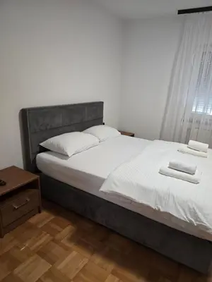 a bedroom with a large bed with white sheets and pillows at Apartmani Zlatna Kruna in Banja Luka