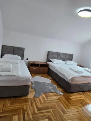 two beds in a room with a wooden floor at Apartmani Zlatna Kruna in Banja Luka