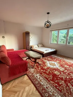 a living room with a red couch and a bed at Comfort house near pyramids II in Visoko