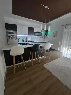a kitchen with three chairs and a table and a counter at Apartman Nia in Bihać