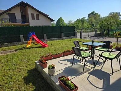 a patio with a table and chairs and a playground at Apartman Nia in Bihać