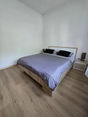 a bedroom with a large bed and a wooden floor at Apartman Nia in Bihać