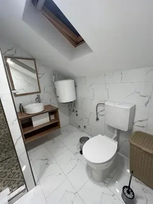 a white bathroom with a toilet and a sink at Apartmani Venecia in Prozor