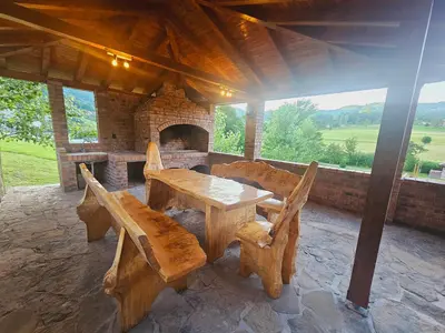 a wooden table and chairs on a patio with a fireplace at Villa Rivera in Banja Luka