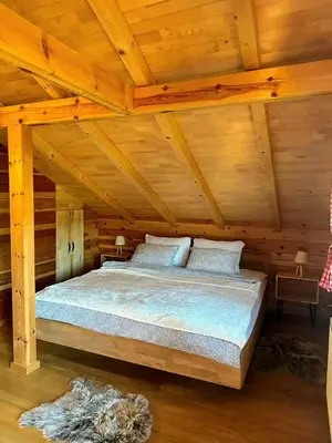 a bed in a log cabin with wooden ceilings at Villa Rivera in Banja Luka