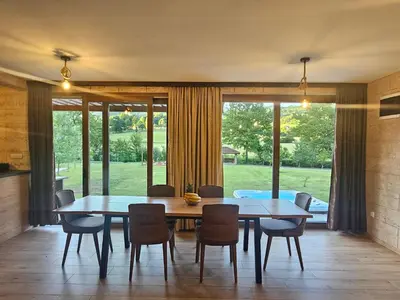 a dining room with a table and chairs and a large window at Villa Rivera in Banja Luka