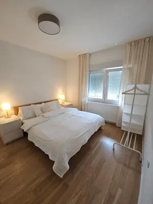 a white bedroom with a large bed and two windows at Apartment DANICA in Banja Luka