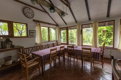 a dining room with a table and chairs and a clock at Vikendica Harun in Bihać