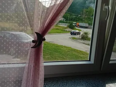 a window with a pink curtain and a car on a street at Apartman Edwin Jajce in Jajce
