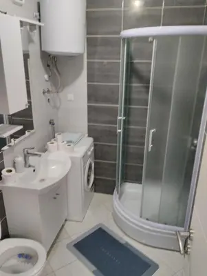 a bathroom with a shower and a toilet and a sink at Apartman Central in Doboj
