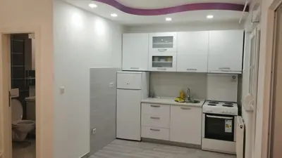 a kitchen with white cabinets and a stove top oven at Apartman Central in Doboj