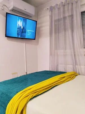 a bedroom with a bed with a tv on the wall at Apartman Central in Doboj