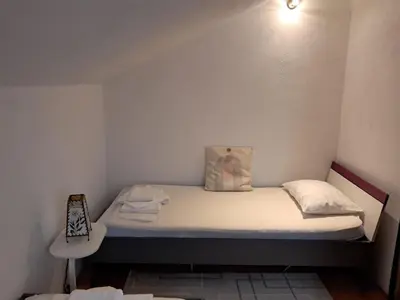 a small bed in a small room with a white wall at Kuca za odmor Amber in Bihać