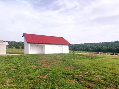 a white barn with a red roof in a field at Antiva in Livno